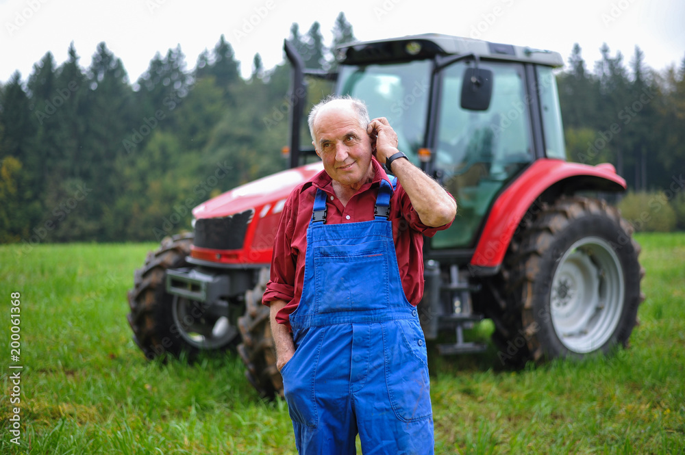 Proud farmer standing in front of his red tractor Stock Photo | Adobe Stock