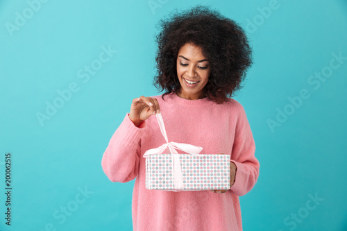 Slika na platnu Portrait of american woman 20s with afro hairdo unwrapping gift box and smiling
