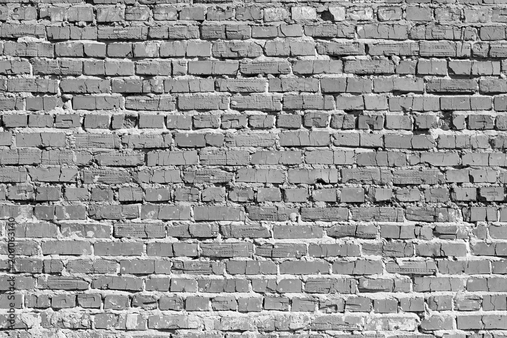 Obraz premium Brick wall. The bricks cracked. Masonry is uneven. Wall is covered or stained with cement mortar. Laying with alternation. Many layers. There are broken bricks. Background, backdrop or Wallpaper.