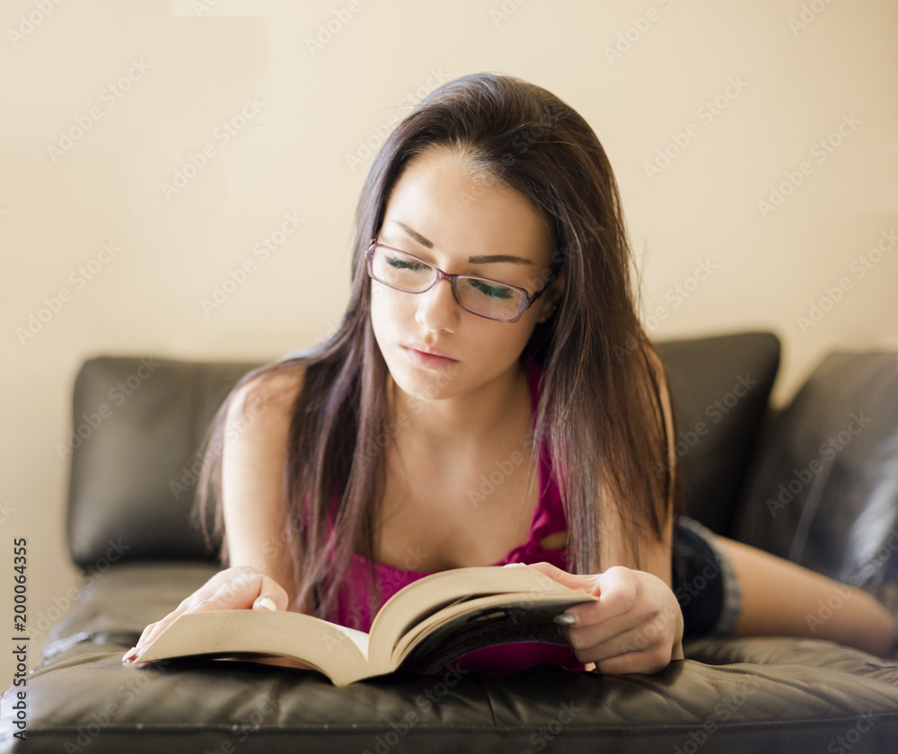 young woman reading a book on the couch young woman reading a book on the couch