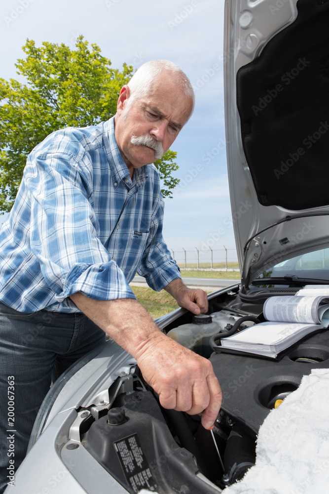 retired man servicing his car engine