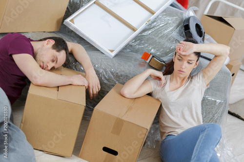 tired couple resting in new home during moving