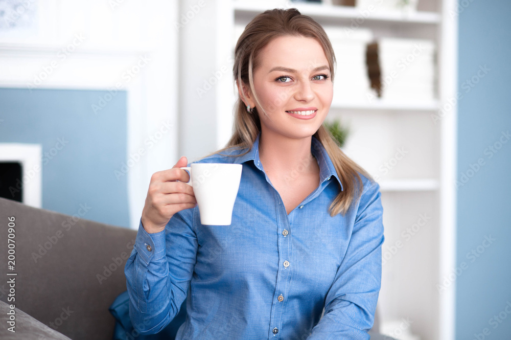 Cute girl smiling, holding coffee in hand and looking at you Cute girl smiling, holding coffee in hand and looking at you