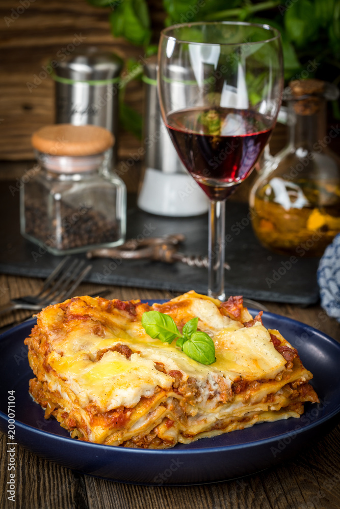 Piece of tasty hot lasagna with red wine.