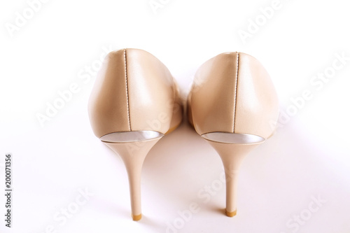 Stylish classic women's beige leather shoes with medium high heels shot from behind, isolated on solid white background. Copy space, top view, flat lay. Shoe sale / clearance ad concept.