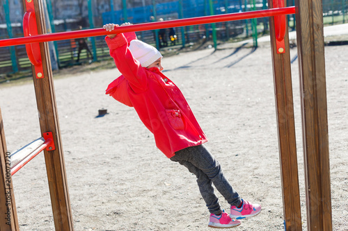 Little girl playing on the horizontal bar photo