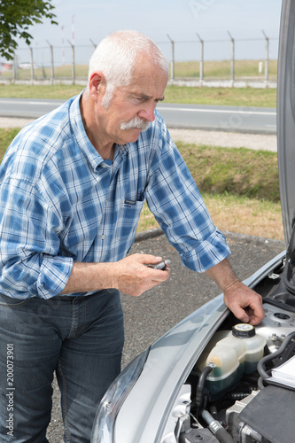older man checking levels and servicing his car