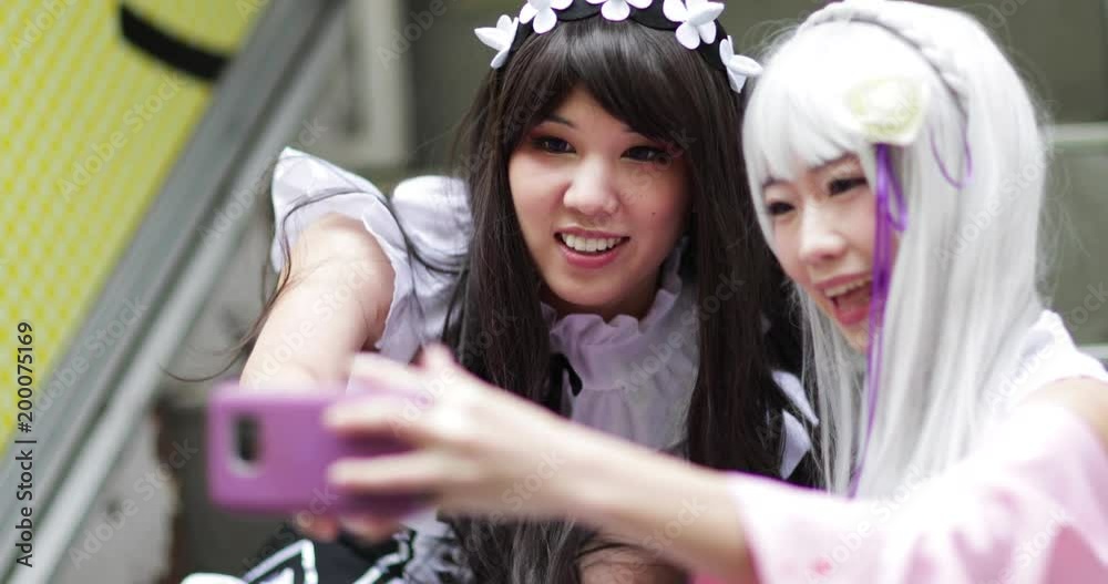 Japanese friends looking at smart phone in Harajuku, Tokyo, Japan