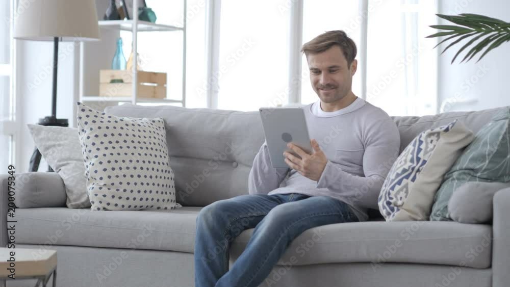 Excited Man Celebrating Success, while Using Tablet Computer Excited Man Celebrating Success, while Using Tablet Computer