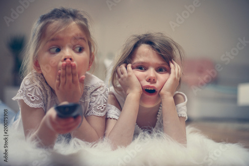 Fotografija Two little sisters watching something shocking on TV