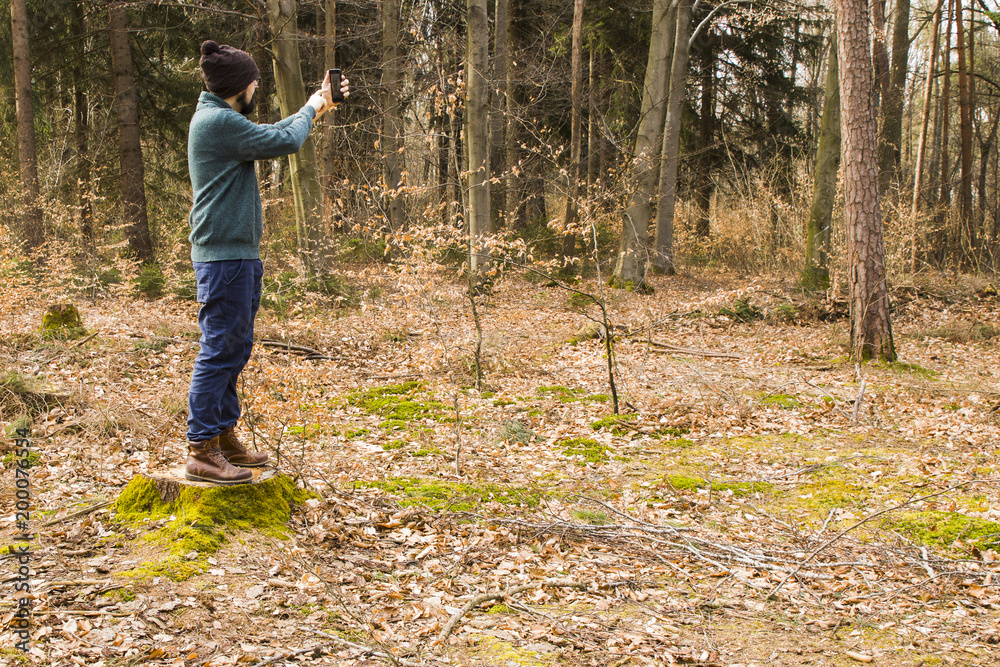 man taking photo with smartphone in the forest man taking photo with smartphone in the forest