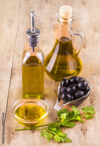 Olive oil with fresh herbs and Black olives on wooden