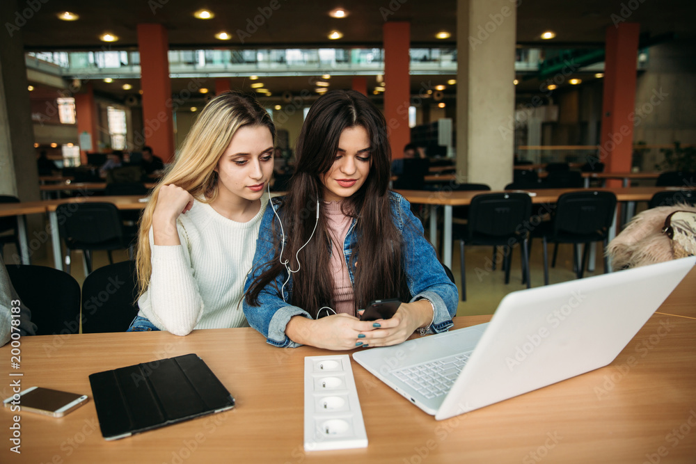 Two girl student use tablet and laptop in library. And listen music Two girl student use tablet and laptop in library. And listen music