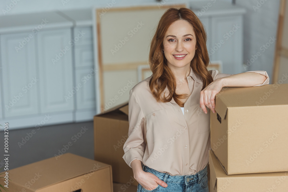 attractive smiling woman leaning on cardboard boxes at new apartment, relocation concept attractive smiling woman leaning on cardboard boxes at new apartment, relocation concept