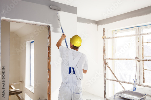 Fototapeta Naklejka Na Ścianę i Meble -  House painter paints a wall in a new home. Unrecognizable Person.