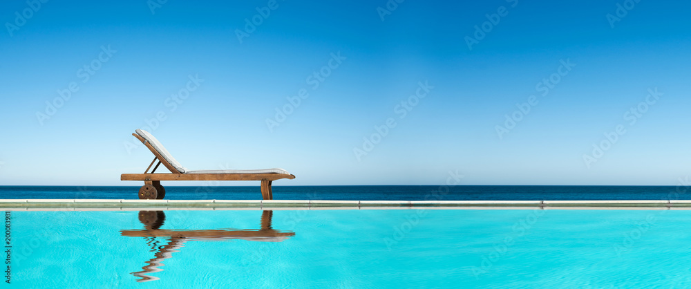 Reclining chair near a swimming pool, sea and blue sky panoramic background - obrazy, fototapety, plakaty 