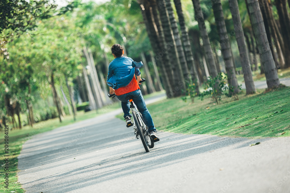 Obraz premium cyclist use cellphone while riding bike in tropical park