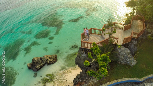 A beautiful light green coast with reefs and a loving couple on the balcony above the beach. The beautiful nature of the Philippines. Aerial view. Near open pool. photo