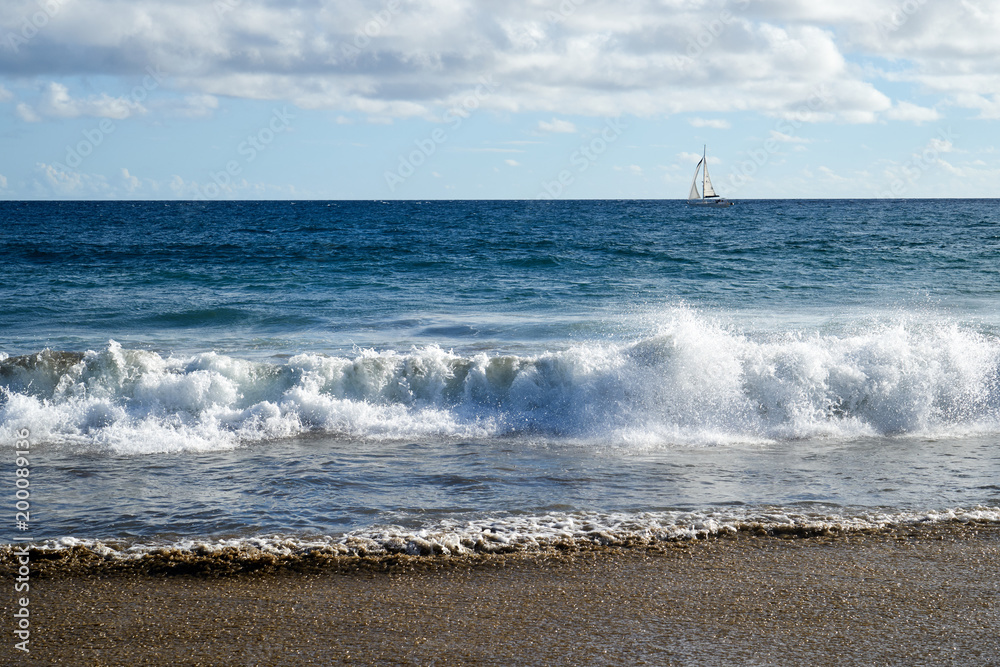 Atlantikküste mit Wellen und einem Segelboot am Horizont