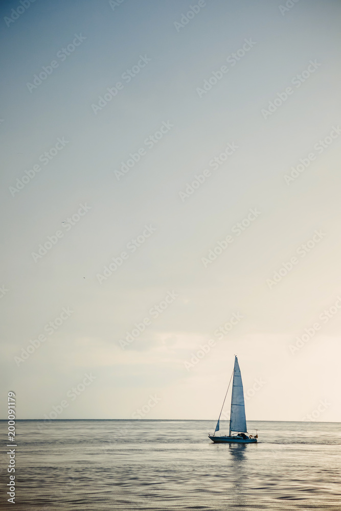 Sailing boat on open sea at sunset.