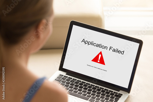 Fotografie Girl looking at laptop with Application Failed error on screen