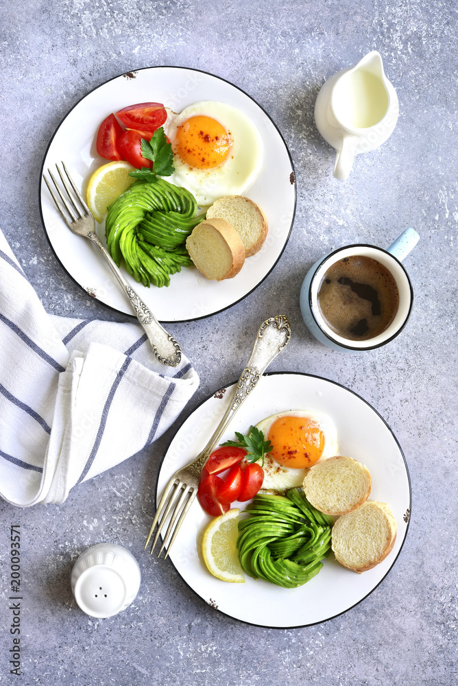 Two breakfast plates with fried egg, avocado rose and baguette.Top view. Two breakfast plates with fried egg, avocado rose and baguette.Top view.