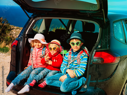 happy kids- little boy and girls- enjoy travel by car at beach