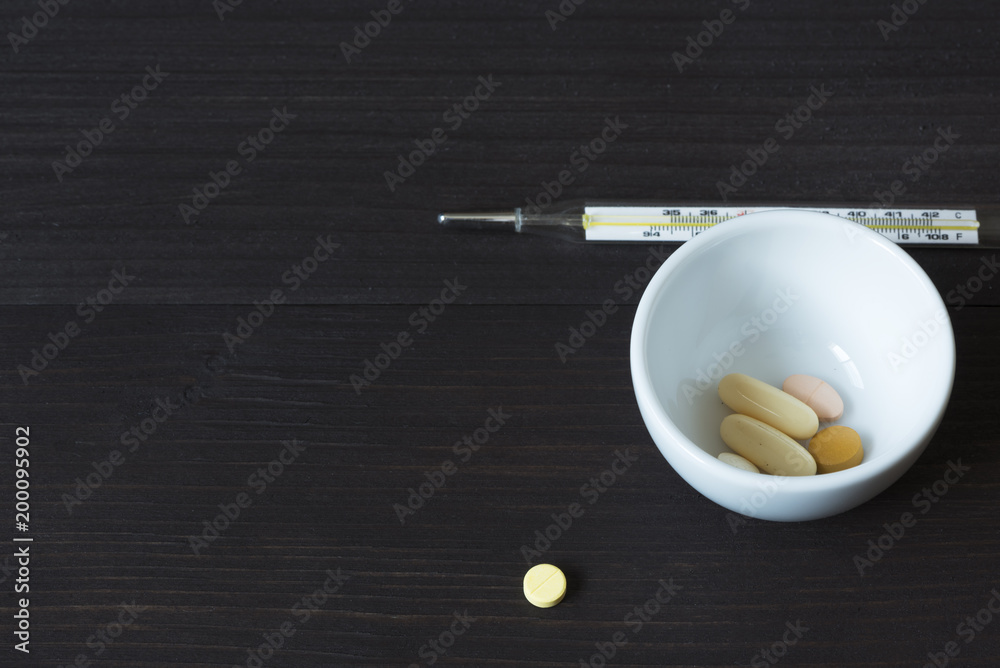 Fototapeta premium Medications and thermometer on wooden background