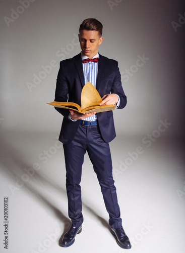 a man, a guy in a blue suit, stands and reads an old book, the concept of knowledge, study, science, business, everything new, it's a well-forgotten old