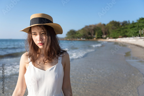 Portrait of pretty woman is lonely and walking alone on beach. Summer concept.