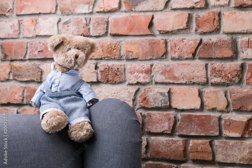 teddy bear sitting on the armchair on a background of a brick wall teddy bear sitting on the armchair on a background of a brick wall