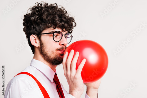 Portrait of a young man with balloon in a studio. © Halfpoint
