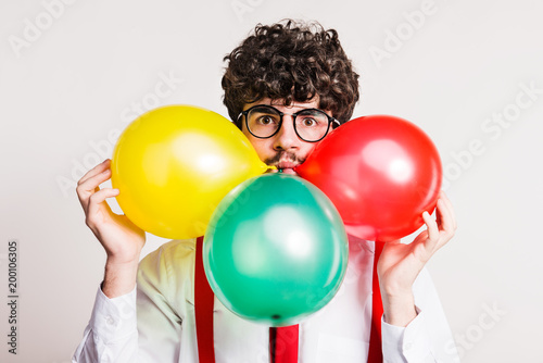 Portrait of a young man with balloons in a studio. © Halfpoint