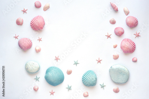 Summer time concept with painted pink and blue sea shells, starfish and stones on a white surface. Flat lay. Top view. . Frame of shells and starfish.