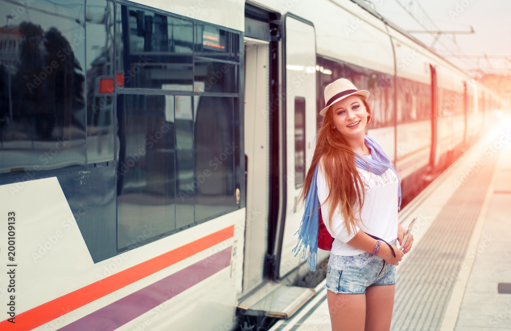 Traveler girl with map, hat and backpack walking train on railway platform. Traveler girl with map, hat and backpack walking train on railway platform.