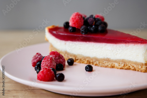 close-up of raspberries and blueberries on a cheesecake background on a pink plate on a wooden table