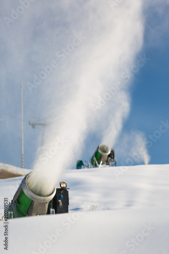 Snow-machine bursting artificial snow over a skiing slope to alow for the skiing season to start