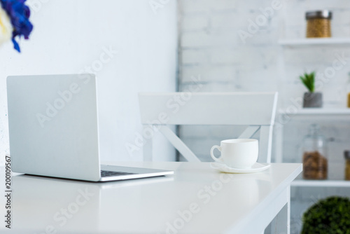 laptop and cup of coffee on white table kitchen