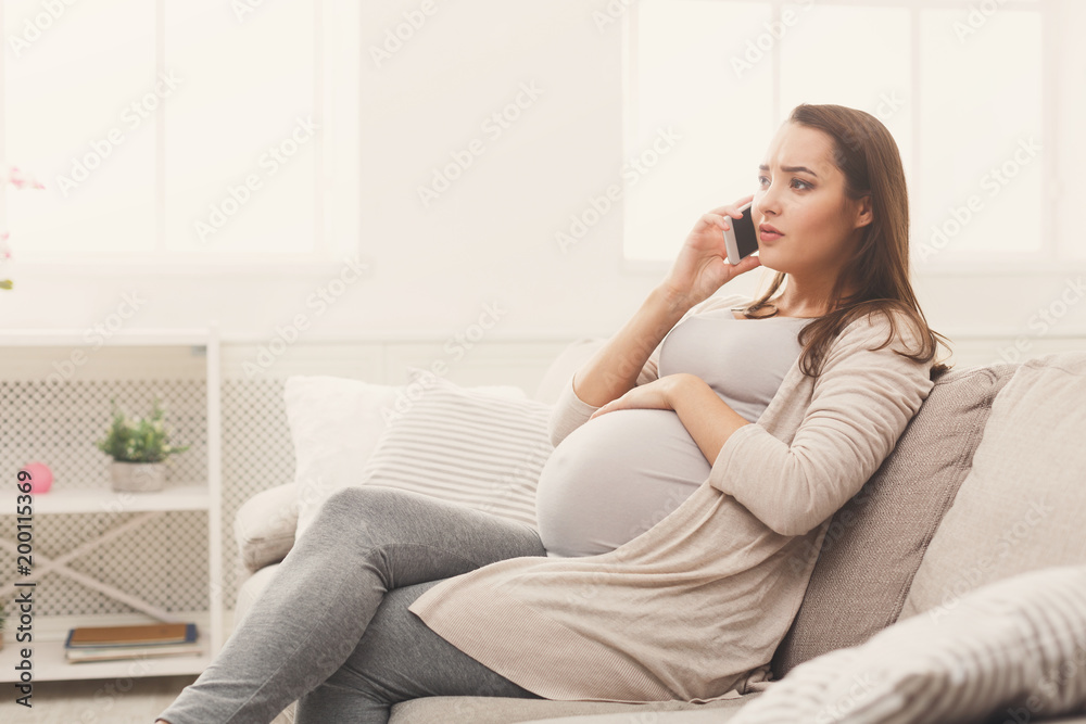 Worried pregnant woman talking on her smartphone Worried pregnant woman talking on her smartphone