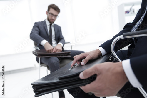 Man in a classic suit holds a brown briefcase close-up