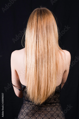 Back view of young sexy girl in black lace body and blonde hair isolated on black. Elegant woman undressing. Erotic noir concept. Body detail.