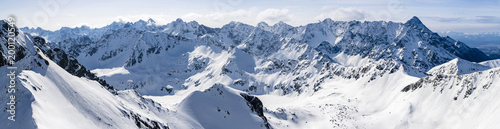 A large wide panorama of a mountain landscape covered with snow.