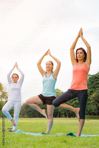 Yoga at park.family couple exercising outdoors. Concept of healthy lifestyle.women exercising in the park.