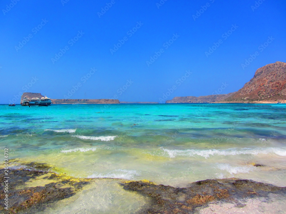 Balos lagoon on Crete island, Greece. Tourists relax and bath in crystal clear water of Balos beach.
