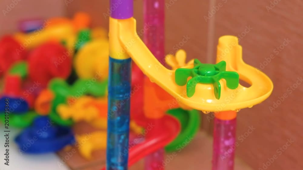 Glass balls roll from the plastic slide of colored designer in the bathroom. Glass balls roll from the plastic slide of colored designer in the bathroom.