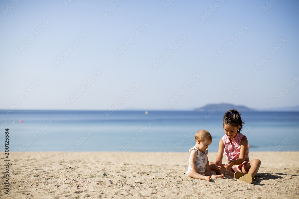 Cute little sisters sitting on a beach