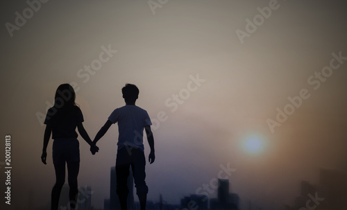 silhouette of a couple walking in a city at dawn or dusk with sky sunset.