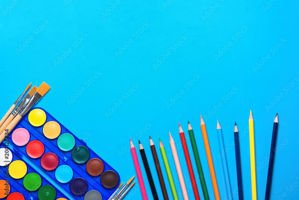 Fototapeta premium Palette with Rows of Multicolored Watercolor Paints Brushes Pencils on Blue Background. Arts School Class Creativity Painting Hobbies Kids Education Concept. Poster Banner Streamer Template
