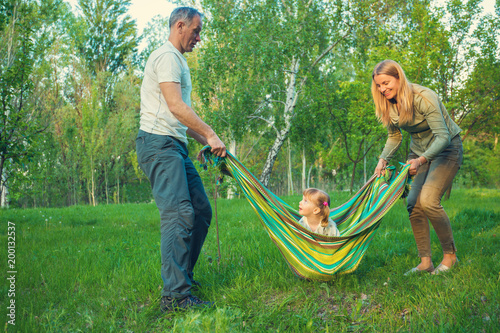 Joyful parents play with their little daughter in a park