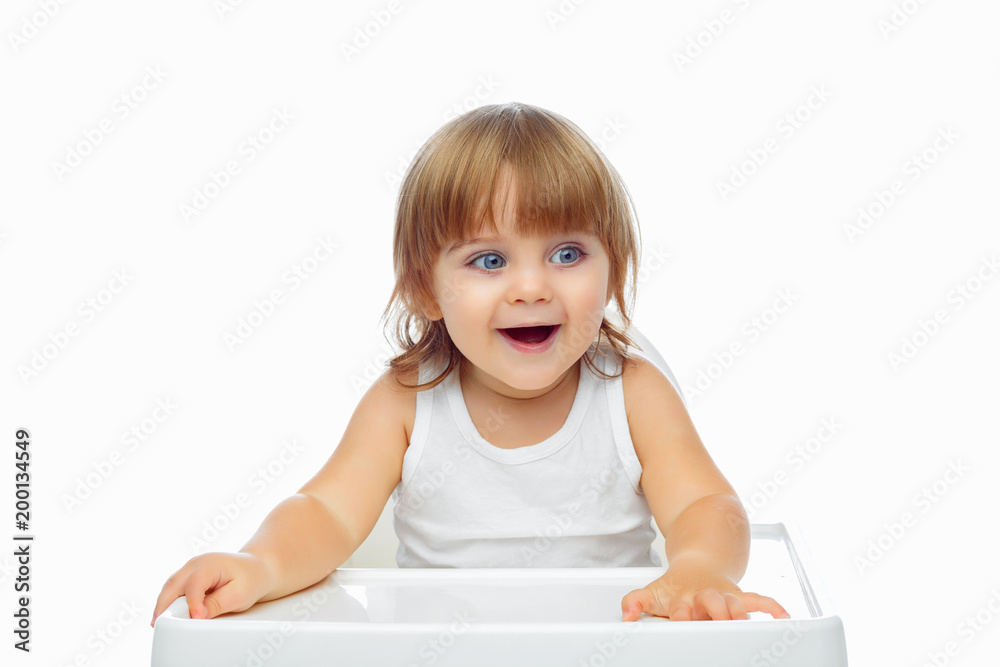 a handsome baby 1.6 years old sits in a white child's highchair. The concept of baby food. Food. a handsome baby 1.6 years old sits in a white child's highchair. The concept of baby food. Food.